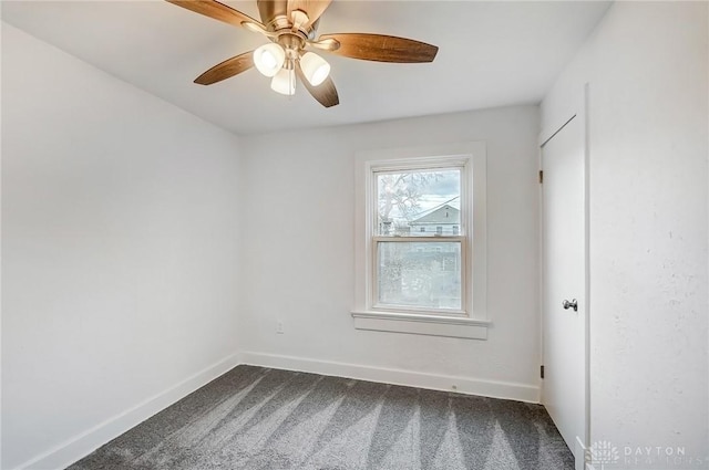 empty room with a ceiling fan, dark colored carpet, and baseboards