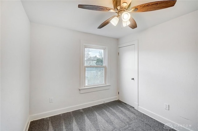 spare room with baseboards, dark carpet, and ceiling fan