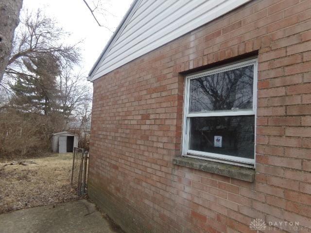 view of side of property with brick siding, an outdoor structure, and a shed