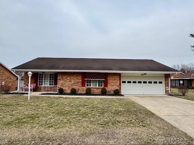 ranch-style house featuring a front yard, concrete driveway, brick siding, and an attached garage