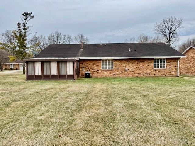 back of property with a yard, brick siding, and central air condition unit