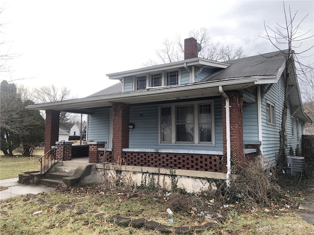 bungalow-style home featuring a chimney, a porch, and cooling unit