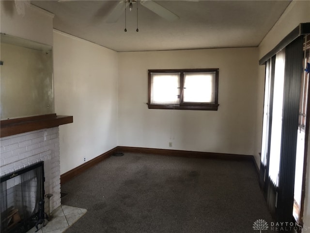 unfurnished living room with ceiling fan, carpet floors, a fireplace, and baseboards