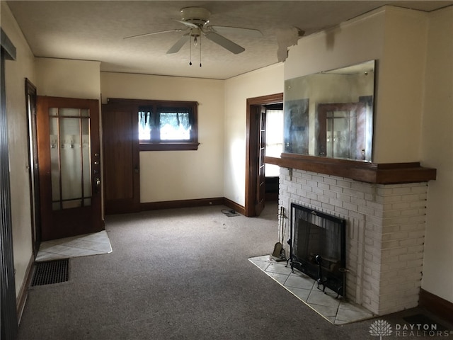 unfurnished living room featuring a ceiling fan, baseboards, visible vents, a brick fireplace, and carpet