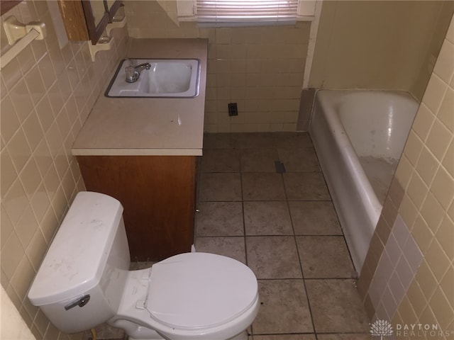 full bath with toilet, vanity, tile walls, and tile patterned floors