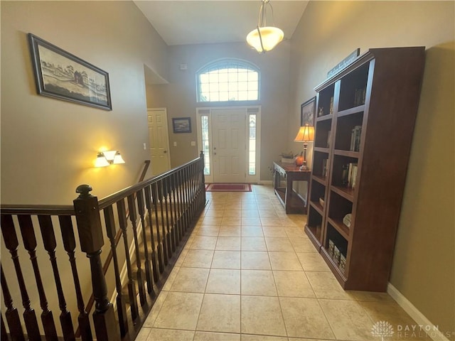 entryway with baseboards, a high ceiling, and light tile patterned floors