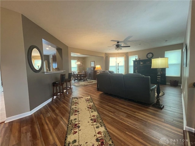 living room featuring a ceiling fan, dark wood-style flooring, and baseboards