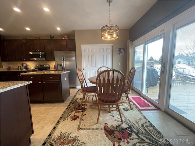 kitchen featuring light tile patterned floors, stainless steel appliances, dark brown cabinets, and decorative light fixtures