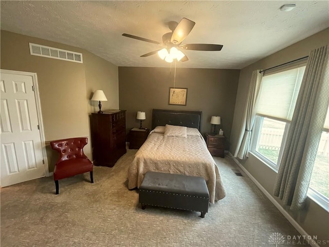 carpeted bedroom with a ceiling fan, visible vents, a textured ceiling, and baseboards