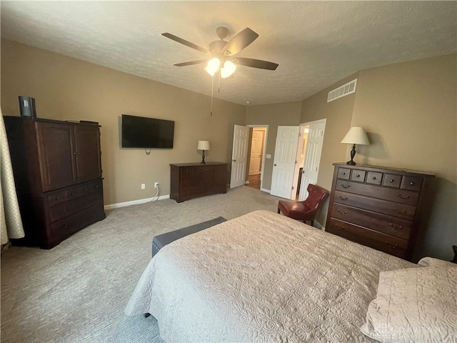 bedroom with baseboards, visible vents, a ceiling fan, light colored carpet, and a textured ceiling