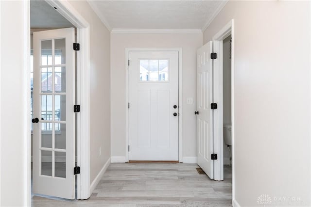 foyer entrance with ornamental molding, light wood-type flooring, and baseboards