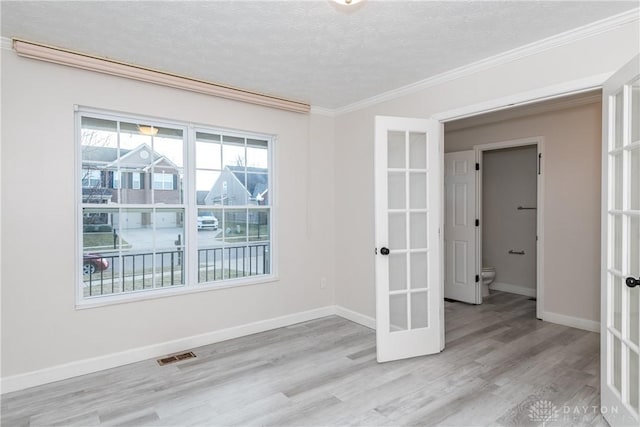 spare room with baseboards, visible vents, wood finished floors, and french doors