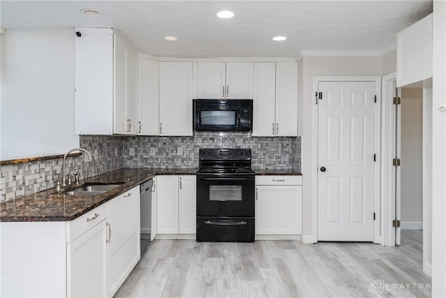 kitchen featuring dark stone countertops, white cabinets, a sink, and black appliances