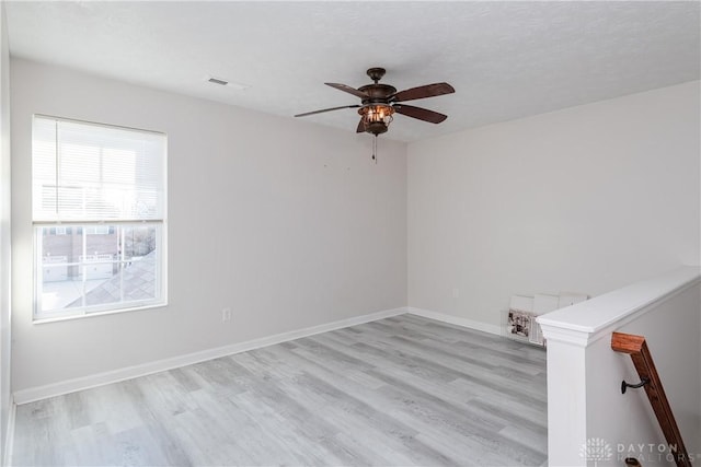 unfurnished room with light wood-style floors, visible vents, ceiling fan, and baseboards