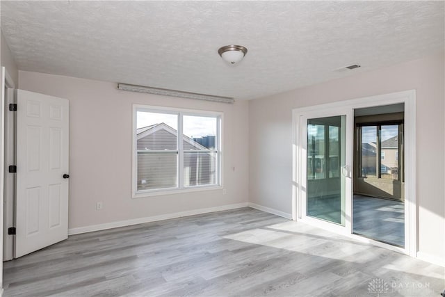 unfurnished room with light wood-type flooring, visible vents, and baseboards