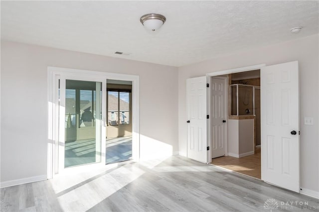 spare room with light wood-type flooring, visible vents, and baseboards