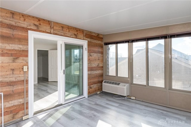 interior space with a wall unit AC, wood walls, and wood finished floors