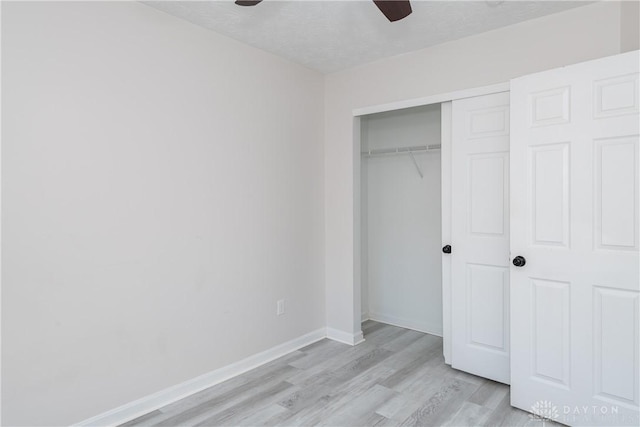 unfurnished bedroom featuring a ceiling fan, light wood-type flooring, a closet, and baseboards