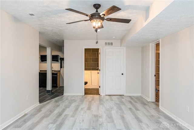 interior space featuring baseboards, visible vents, a textured ceiling, and wood finished floors