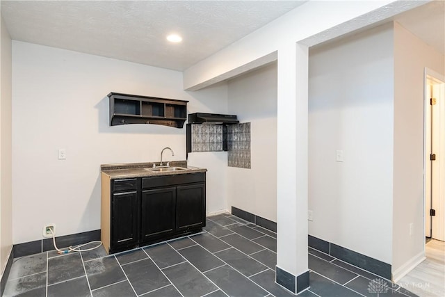 interior space with a sink, under cabinet range hood, and baseboards