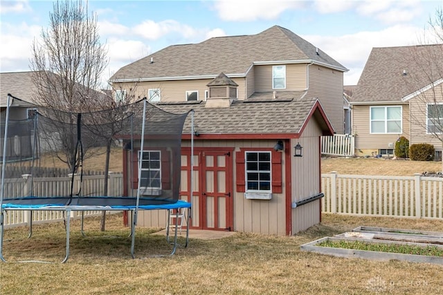 view of shed with a trampoline, fence, and a garden