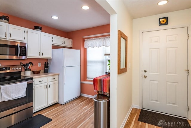 kitchen featuring light wood finished floors, white cabinetry, stainless steel appliances, and light countertops