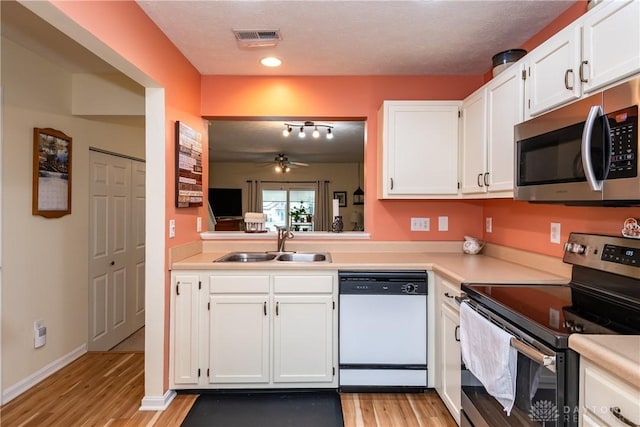 kitchen featuring visible vents, stainless steel appliances, light countertops, white cabinetry, and a sink