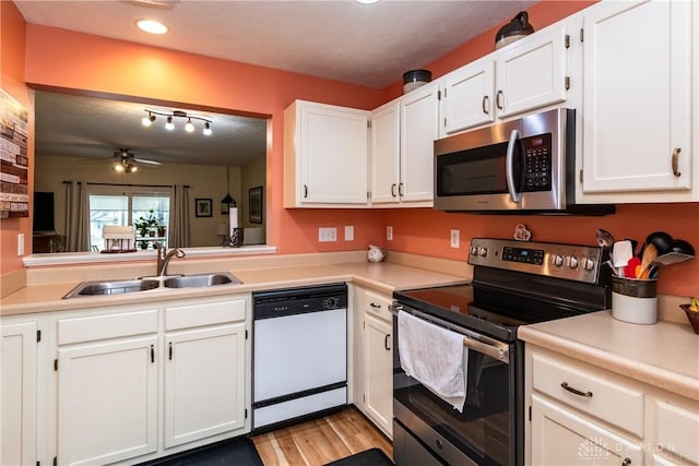 kitchen with stainless steel appliances, light countertops, white cabinets, and a sink