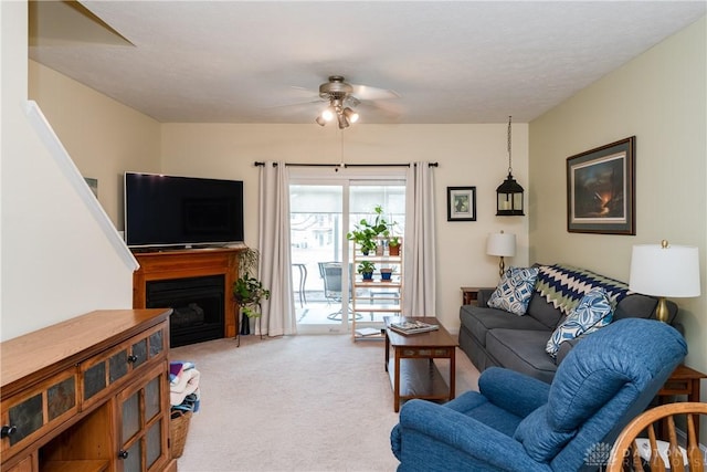 carpeted living room with ceiling fan and a fireplace