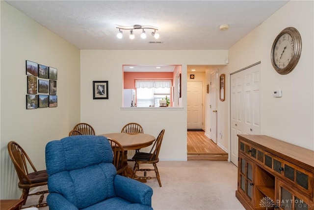 dining room with light carpet, baseboards, and visible vents