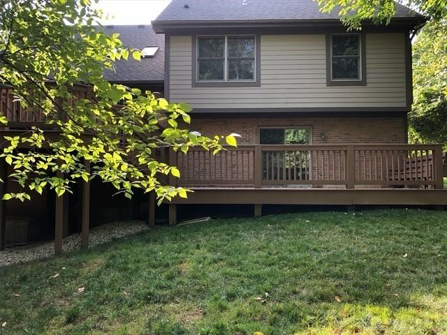 back of house with a yard, a wooden deck, roof with shingles, and brick siding