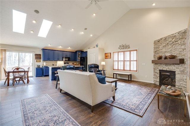 living room with dark wood-style floors, high vaulted ceiling, and a stone fireplace