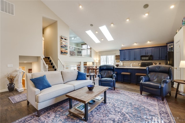 living area with a skylight, visible vents, dark wood-style floors, stairway, and high vaulted ceiling