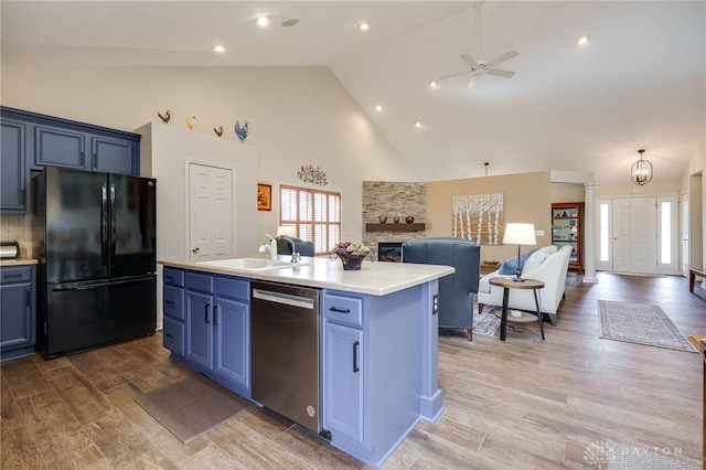 kitchen featuring blue cabinetry, stainless steel dishwasher, freestanding refrigerator, open floor plan, and a sink