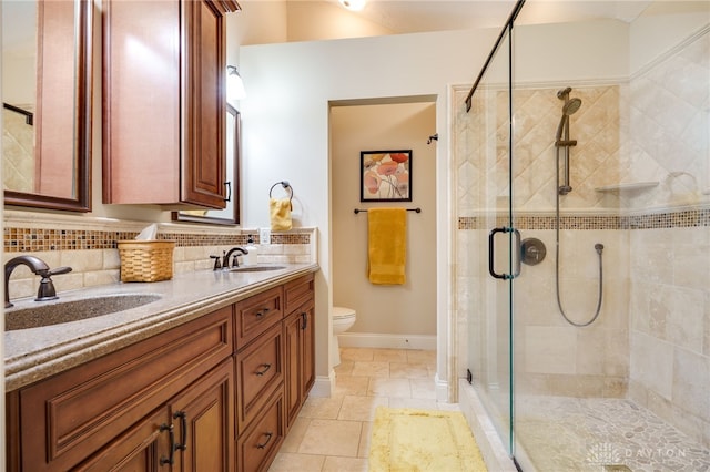 bathroom featuring tasteful backsplash, a stall shower, a sink, and toilet