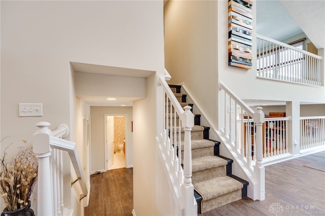 stairs featuring a towering ceiling and wood finished floors