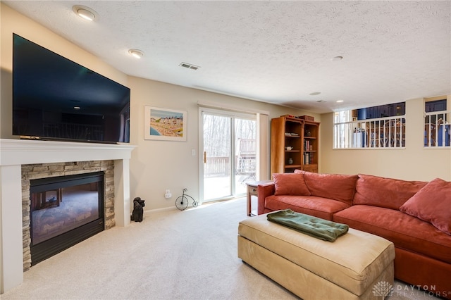 living room featuring a textured ceiling, a fireplace, visible vents, and carpet flooring