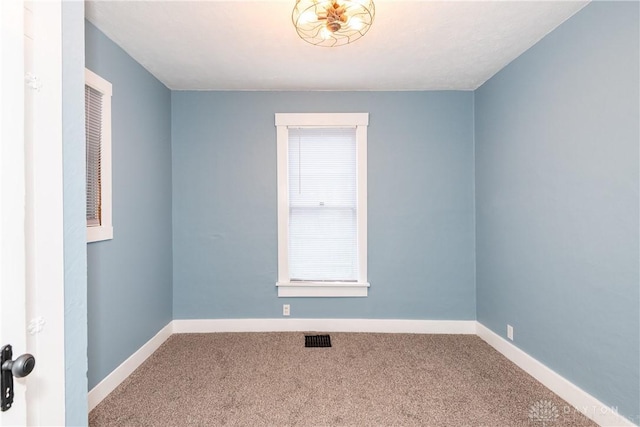 unfurnished room featuring carpet floors, visible vents, and baseboards