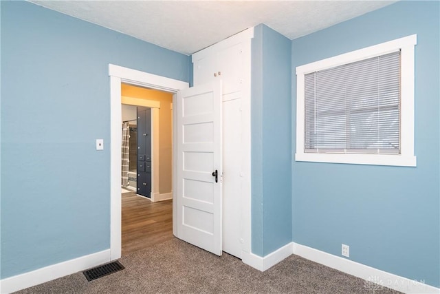 spare room featuring baseboards, visible vents, and carpet flooring