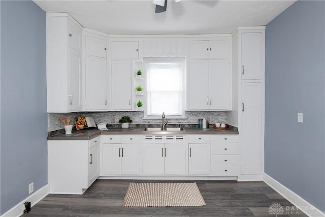 kitchen with dark countertops, tasteful backsplash, white cabinetry, and a sink