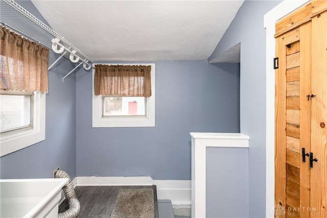 washroom with a textured ceiling, laundry area, and wood finished floors