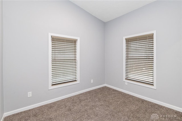 empty room featuring lofted ceiling, carpet, and baseboards