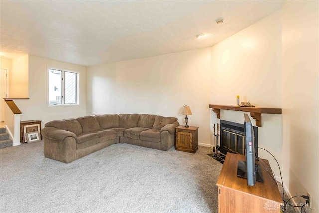 living area featuring a fireplace with flush hearth, stairs, baseboards, and carpet flooring