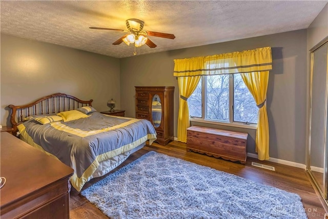 bedroom with baseboards, visible vents, ceiling fan, wood finished floors, and a textured ceiling