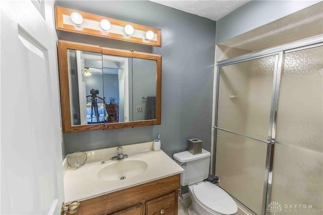 bathroom with toilet, a shower stall, and vanity