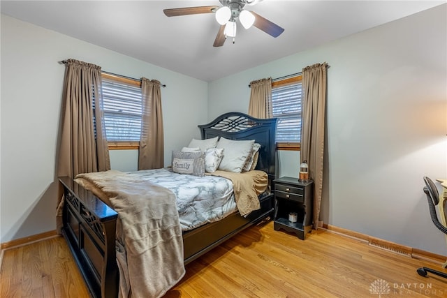 bedroom featuring light wood finished floors, visible vents, baseboards, and ceiling fan