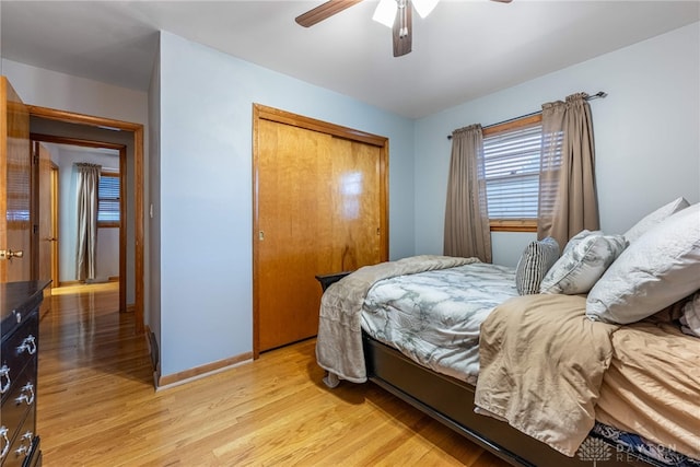 bedroom with a closet, ceiling fan, light wood-style flooring, and baseboards