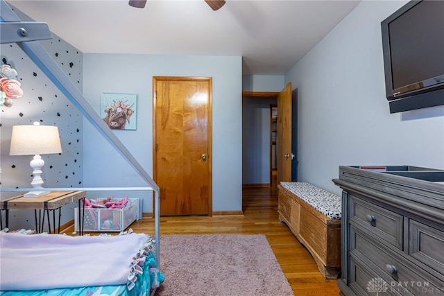 bedroom with light wood-type flooring, a ceiling fan, and baseboards