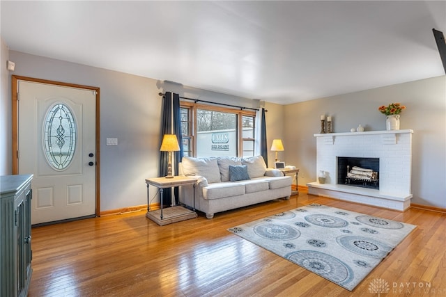 living area featuring a wealth of natural light, a brick fireplace, baseboards, and hardwood / wood-style flooring