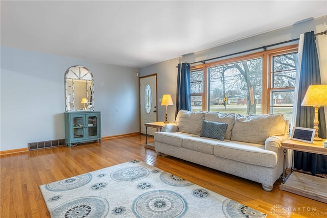 living room with wood finished floors, visible vents, and baseboards